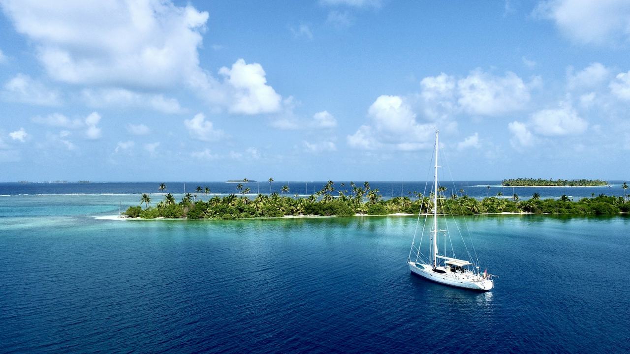 Sailboat anchored next to a palm island in San Blas