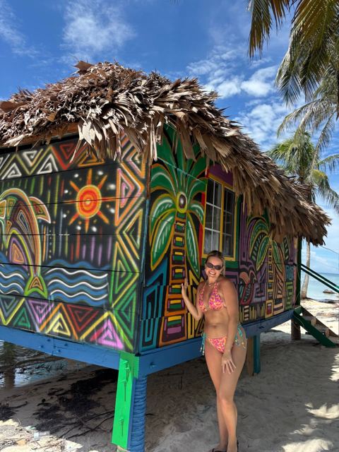Guest next to a cabin painted with Guna-style art