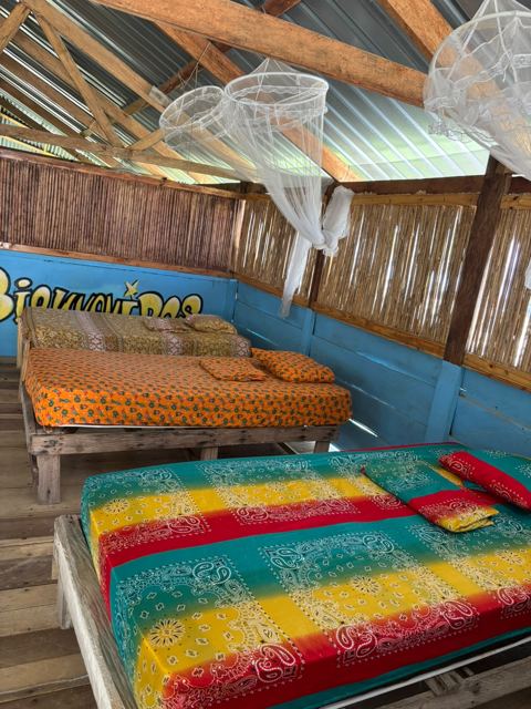 Two beds with colourful covers and mosquito nets